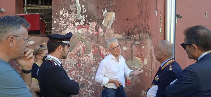 Il presidente della commissione parlamentare Antimafia, Nicola Morra (al centro) mentre parla con il comandante Maiello (a destra) sotto e mura del comando della municipale danneggiate dall'attentato di Capodanno
