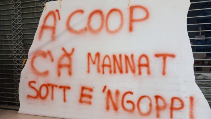 La scritta polemica messa dalle dipendenti Ipercoop sui pezzi strappati del telone di copertura della saracinesca del supermercato di Afragola